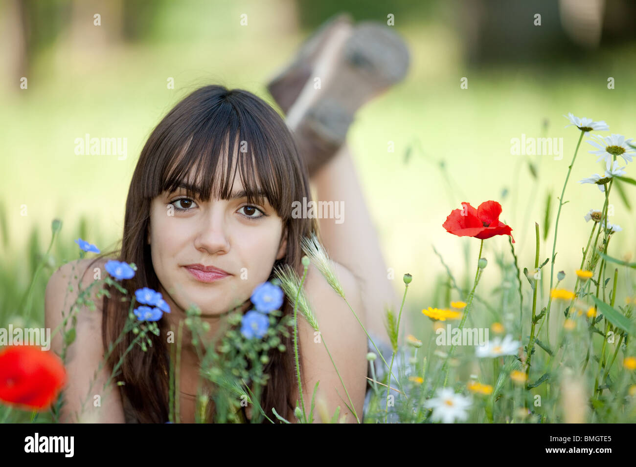 Teen girl lying in wild flowers bed looking at camera Banque D'Images