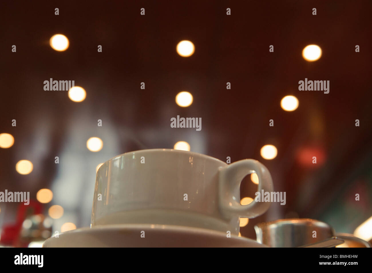 Tasse de café ; Tasse assis sur une soucoupe avec des lumières à l'arrière-plan Banque D'Images