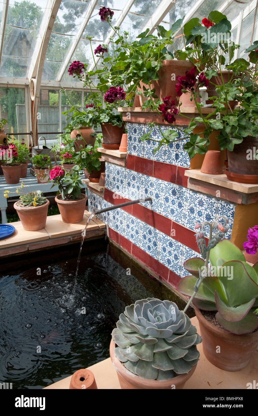 Piscine formelle et de l'eau d'écoulement, avec des pots et des plantes - dans la serre - à Bryan de sol, Stapleton, Herefordshire, UK Banque D'Images