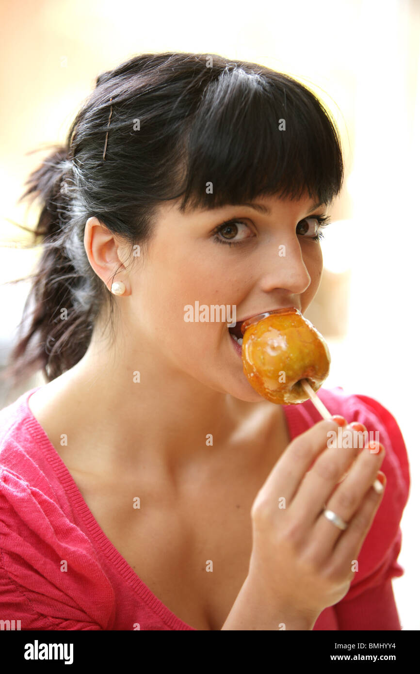 Jeune femme mangeant une pomme caramel. Parution du modèle Banque D'Images