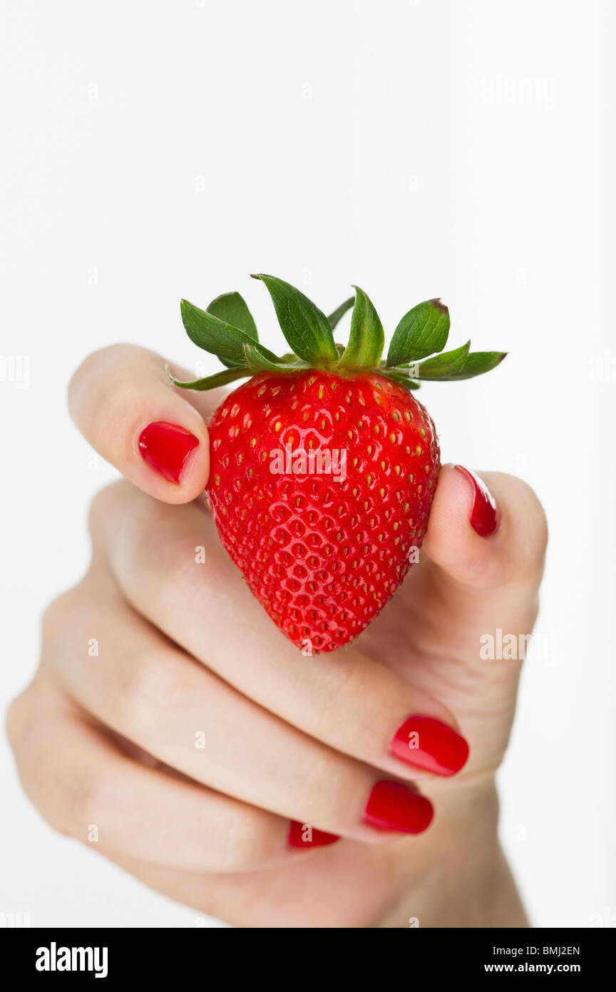 Hand holding red strawberry Banque D'Images