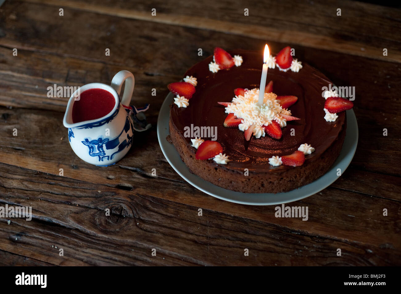 Chocolat Fraise Gateau D Anniversaire Avec Une Bougie Et Une Delfts Blue Pot De Sauce Aux Fraises Photo Stock Alamy
