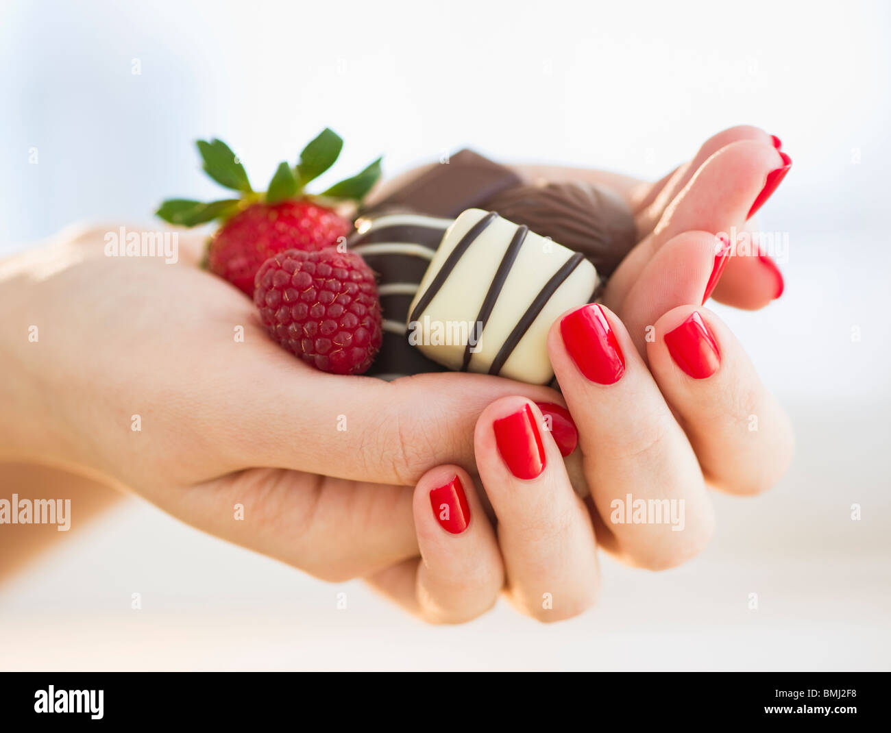 Main tenant un chocolat framboise et une fraise Banque D'Images