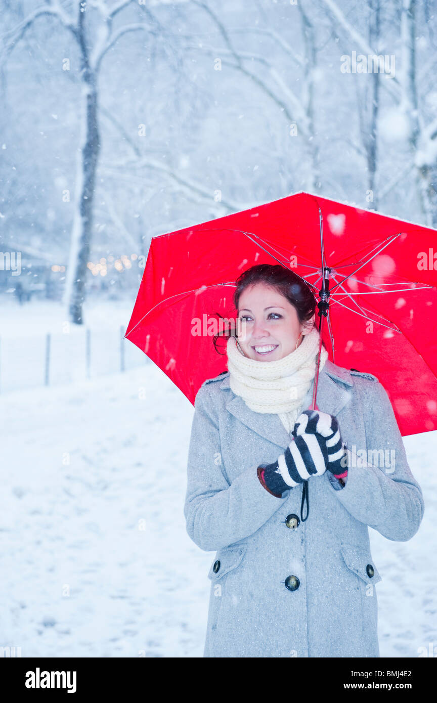Femme marche avec parapluie rouge sur un jour de neige Banque D'Images