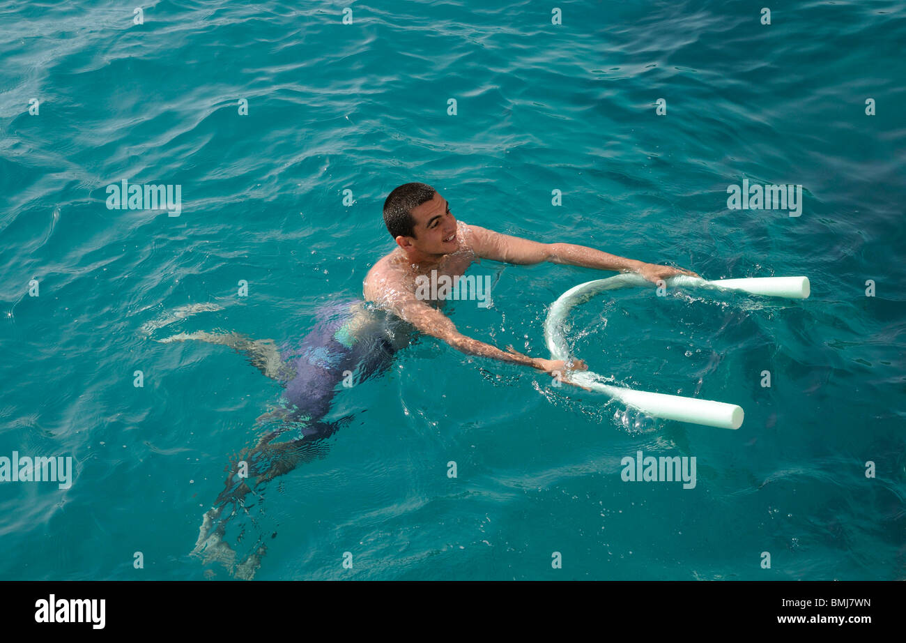 Jeune homme à l'aide d'une piscine et nouilles comme une aide à la flottabilité il flotte dans la mer Banque D'Images