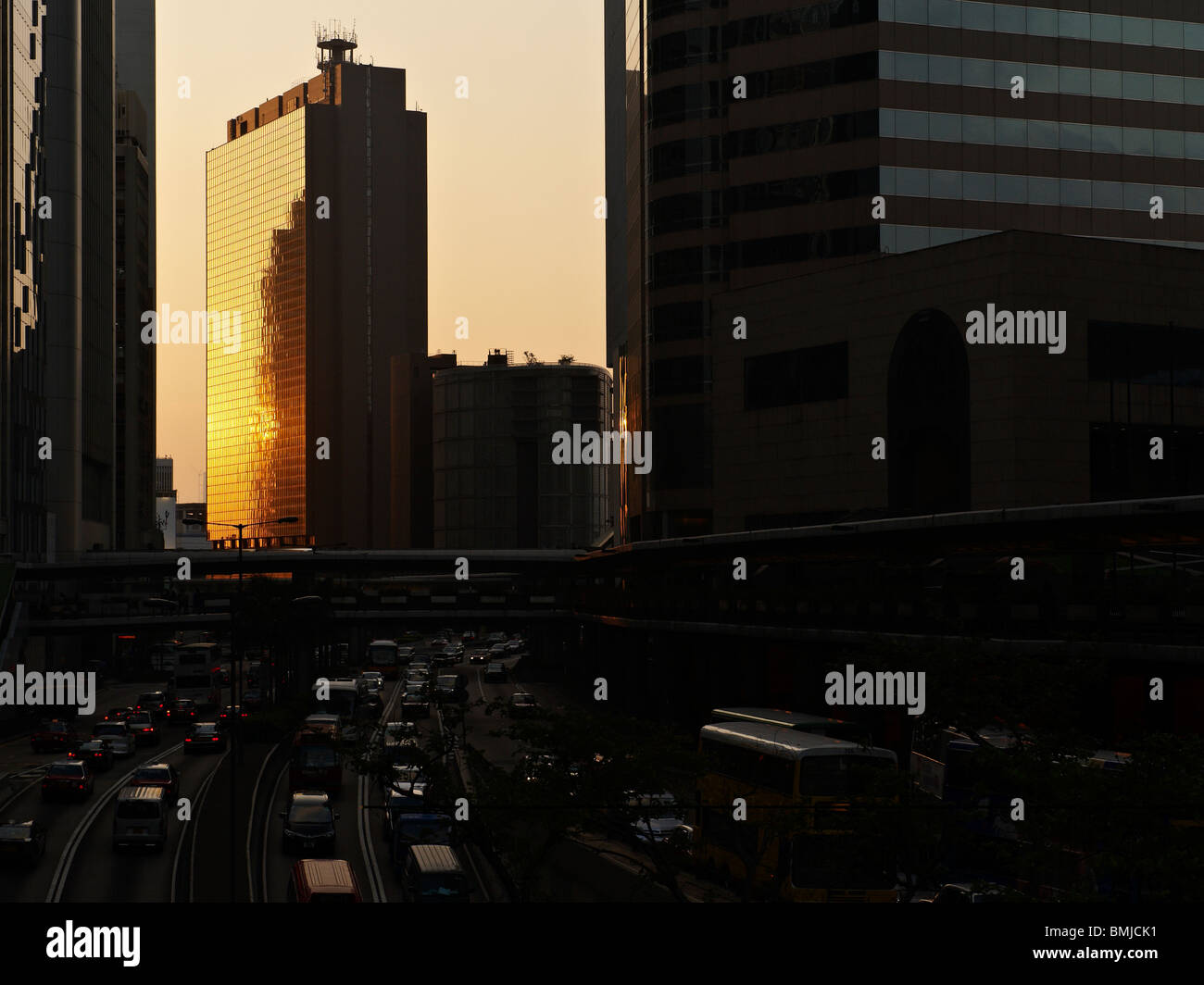 En dernier rayon de soleil reflété sur un gratte-ciel dans le centre de quartier financier de Hong Kong, avec les usagers sur le chemin du retour. Banque D'Images