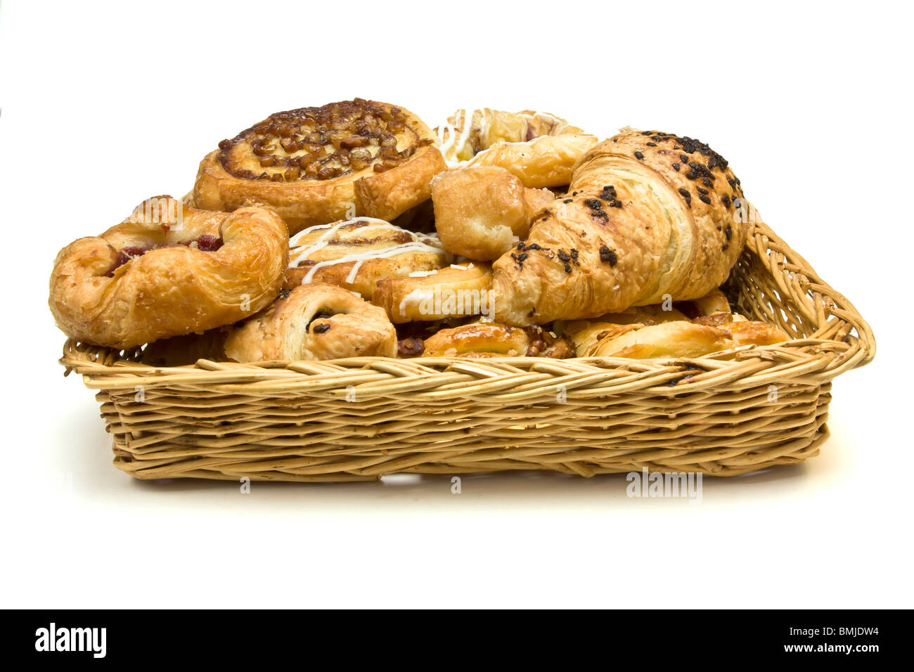 Panier en osier avec sélection de pâtisseries danoises et françaises sur fond blanc. Banque D'Images