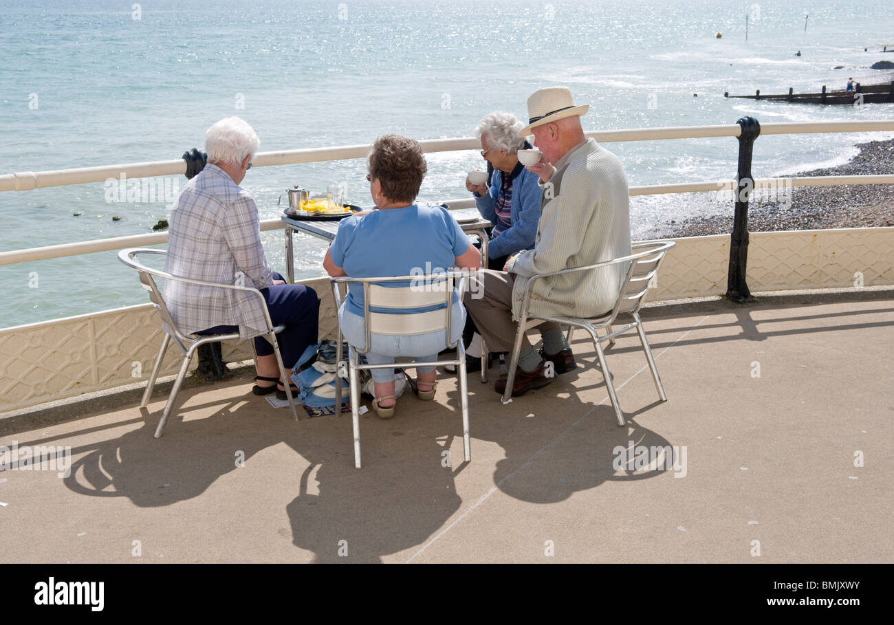 La famille d'un groupe de gens assis à une table et de chaises sur la jetée de Worthing par la mer, sur la côte sud, Sussex UK Banque D'Images