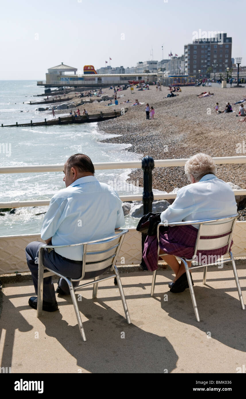 Un couple de personnes âgées, des personnes âgées assis sur la jetée de Worthing surplombant la plage de galets sur la côte sud de Sussex UK Banque D'Images