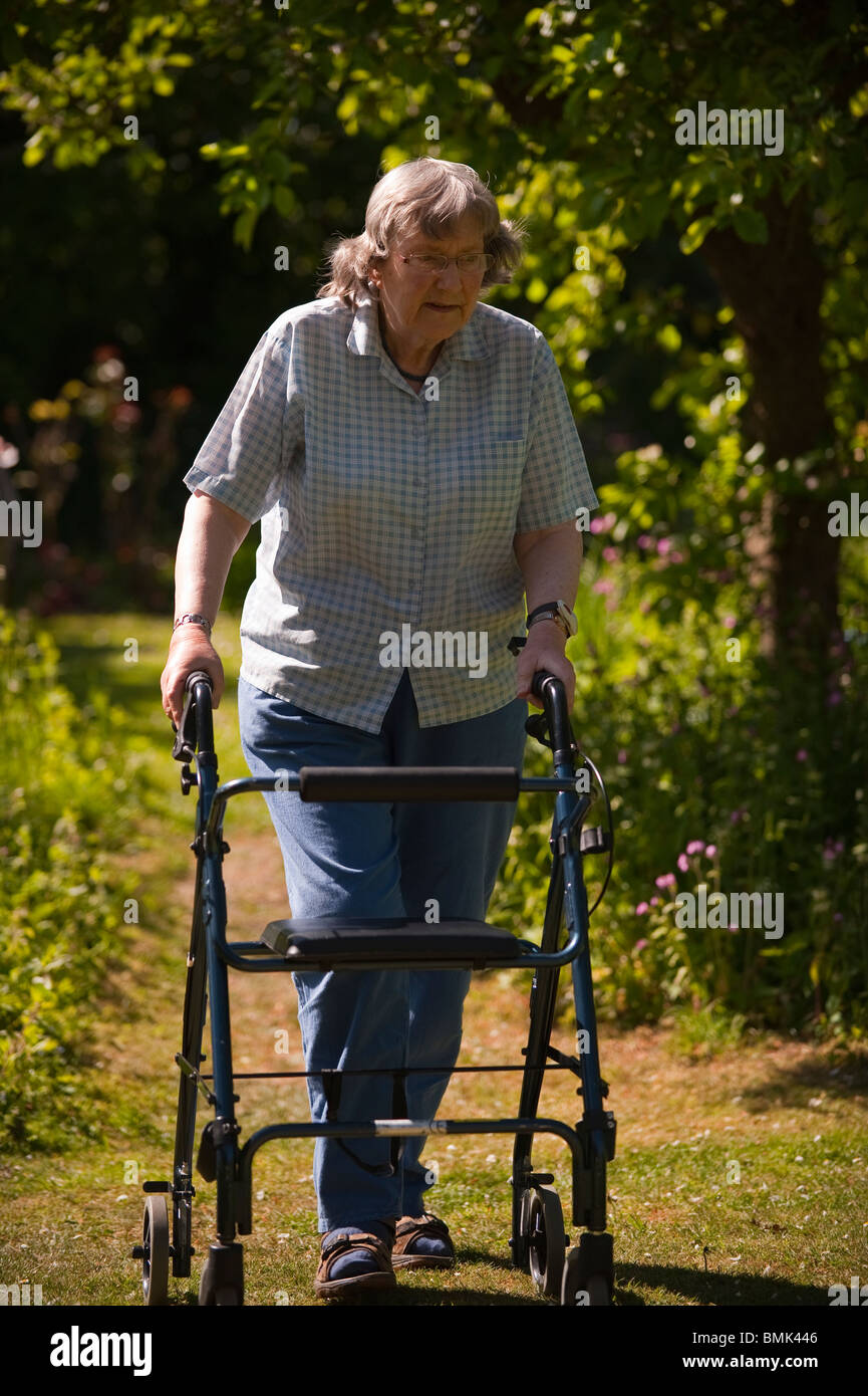 Un modèle femme parution dans son 70's à marcher avec un déambulateur rollator au Royaume-Uni Banque D'Images