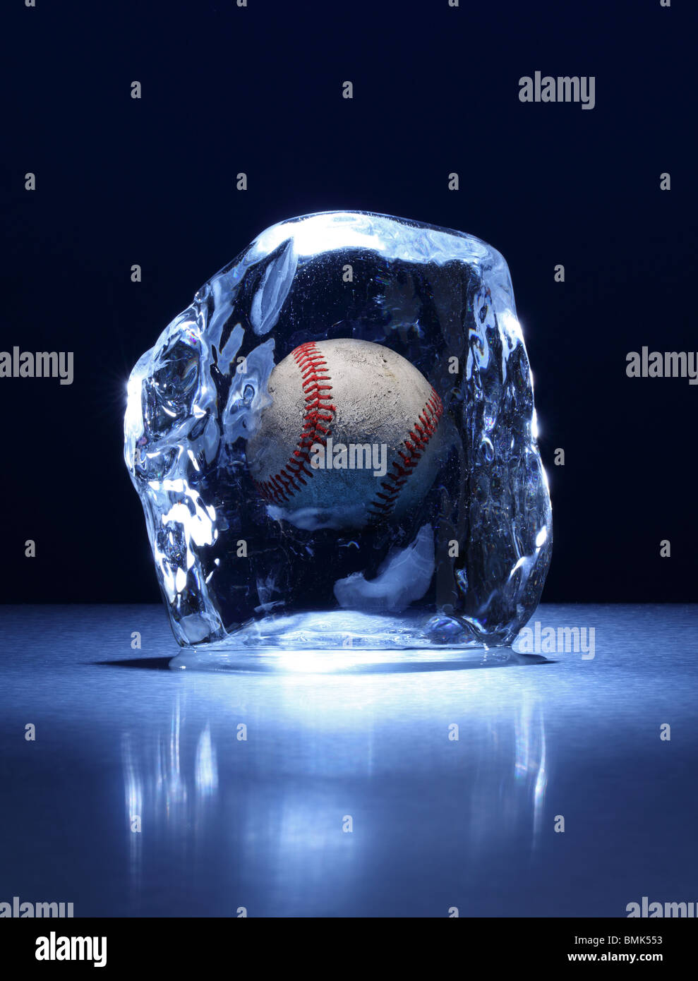 La glace d'un bloc de glace avec un frozen inside baseball sur une surface métallique Banque D'Images