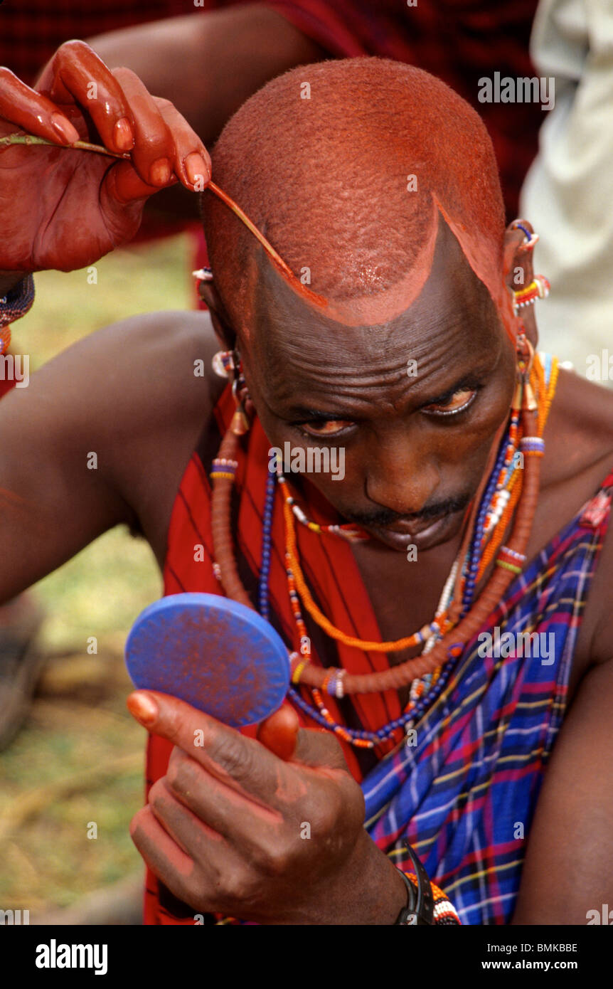 Kenya : Amboseli Massaï, l'homme l'application de la peinture pour le visage ocre pour cérémonie de mariage, mai. Banque D'Images