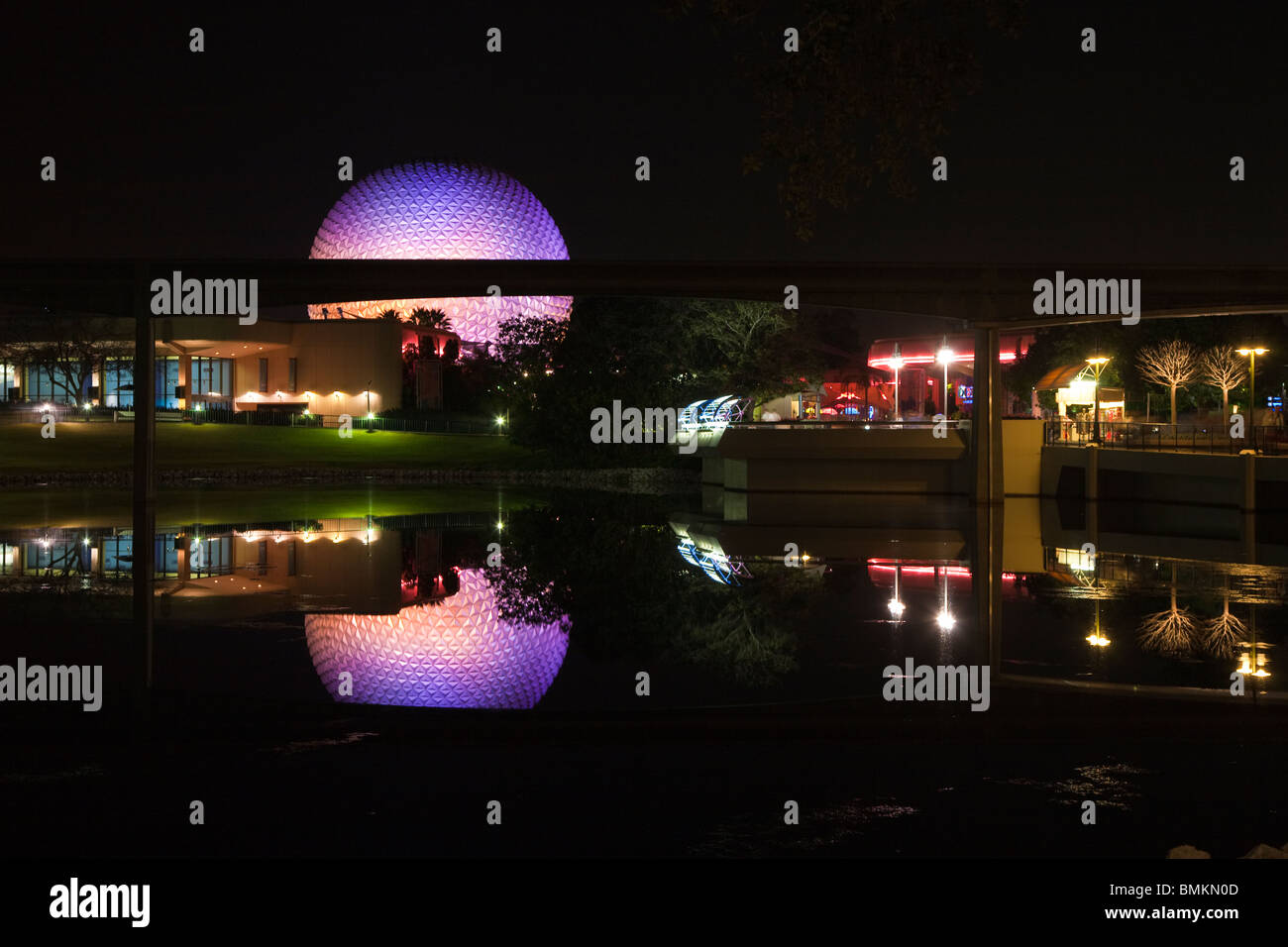 Dôme géodésique de Spaceship Earth attraction éclairé avec des lumières violettes se reflète sur le lac de nuit dans Walt Disney's Epcot Center Banque D'Images