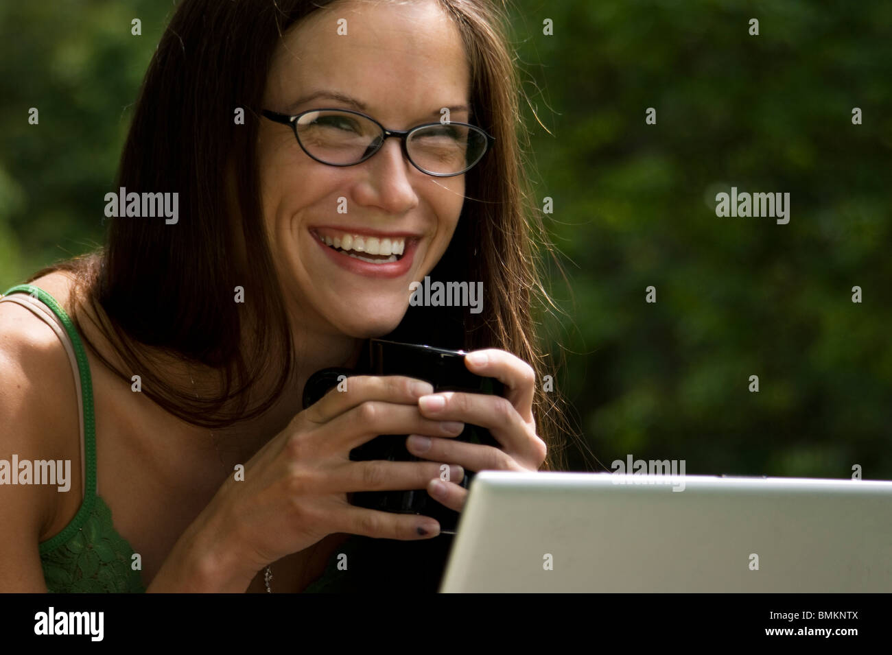 Jolie femme se détend dans le parc ayant le café et travailler sur son ordinateur portable Banque D'Images