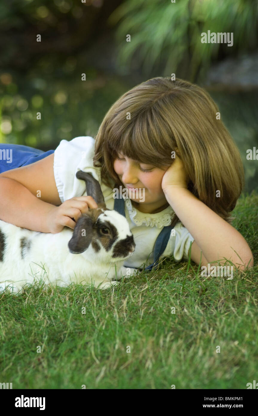 Jeune fille pose dans l'herbe de flatter son Bunny Banque D'Images