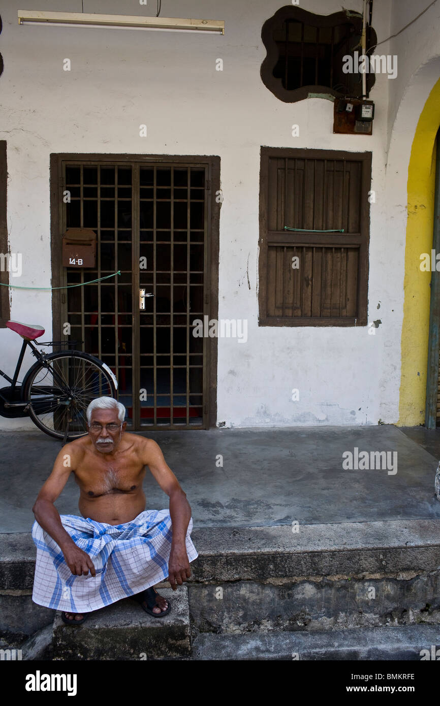Un homme âgé assis sur le trottoir dans le quartier chinois de Penang, Malaisie. Banque D'Images