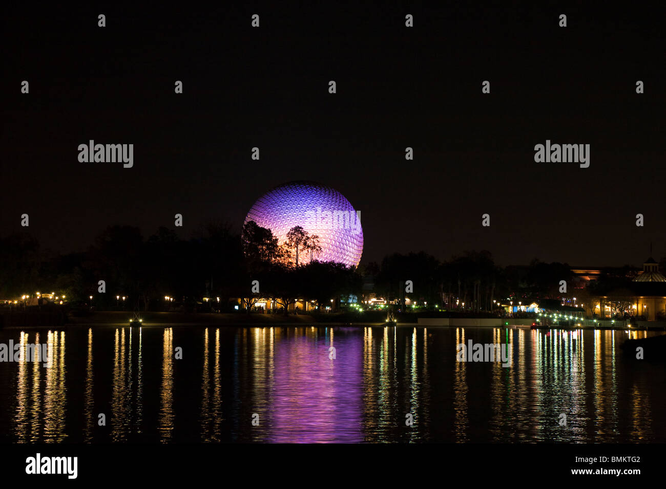 Dôme géodésique de Spaceship Earth attraction éclairé avec des lumières violettes se reflète sur le lac de nuit dans Walt Disney's Epcot Center Banque D'Images