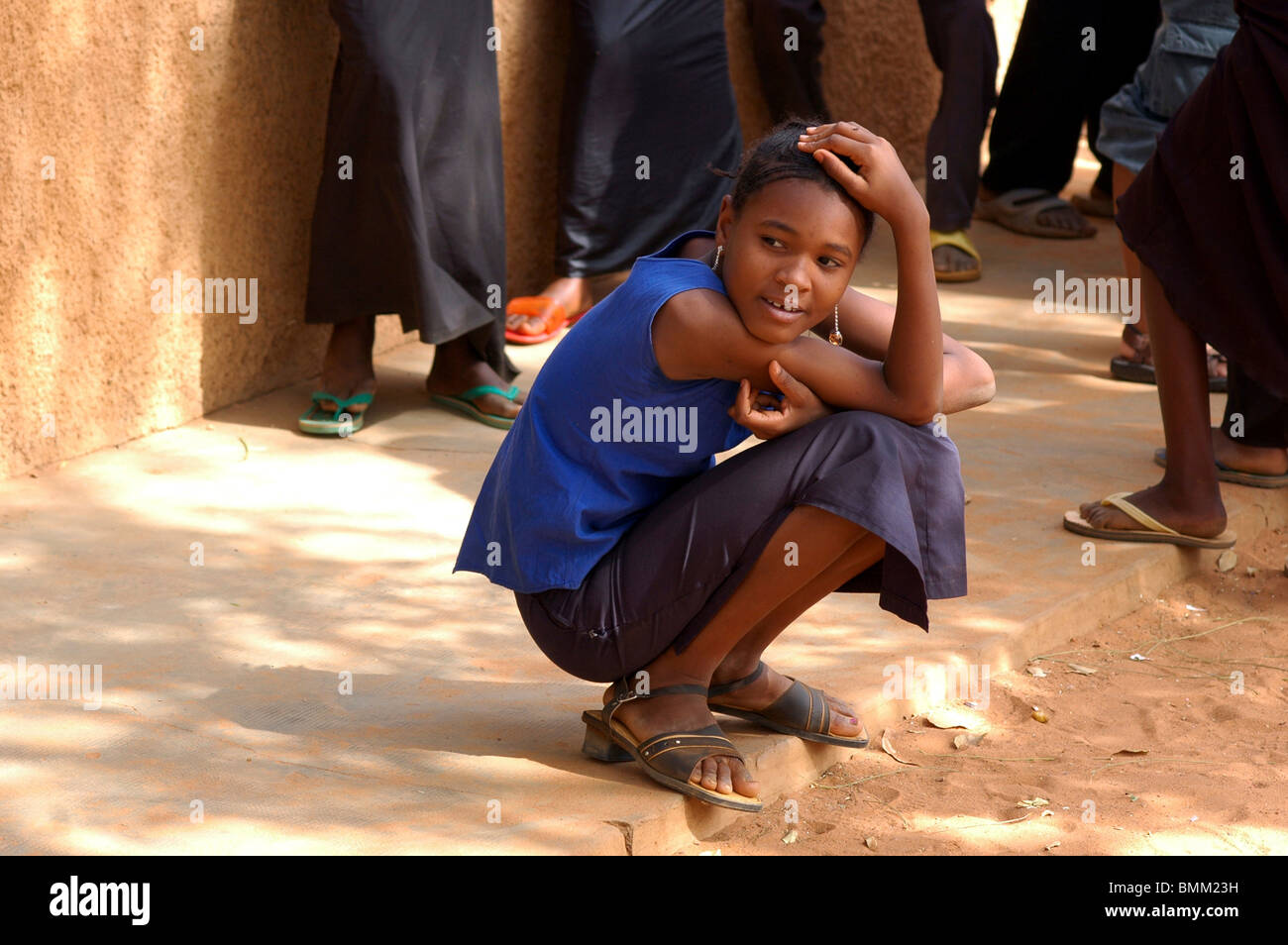 Le Niger, Niamey, Portrait d'un jeune lycéenne dans son uniforme bleu, accroupis. Banque D'Images