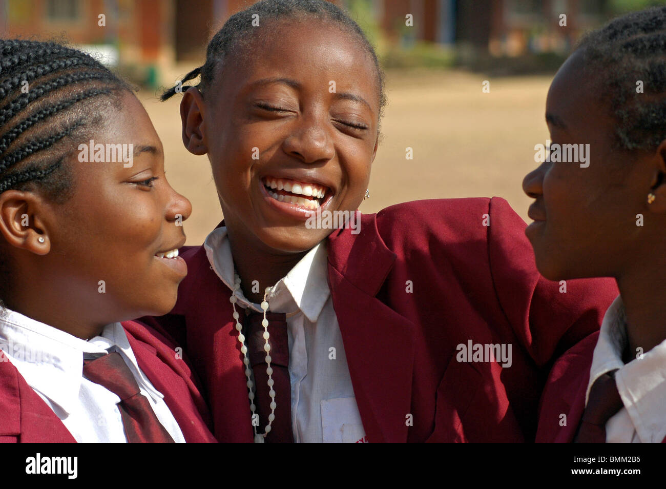 Le Nigéria, Jos, Portrait d'écolières dans leur uniforme violet, sourire et rire, enlacés. Banque D'Images