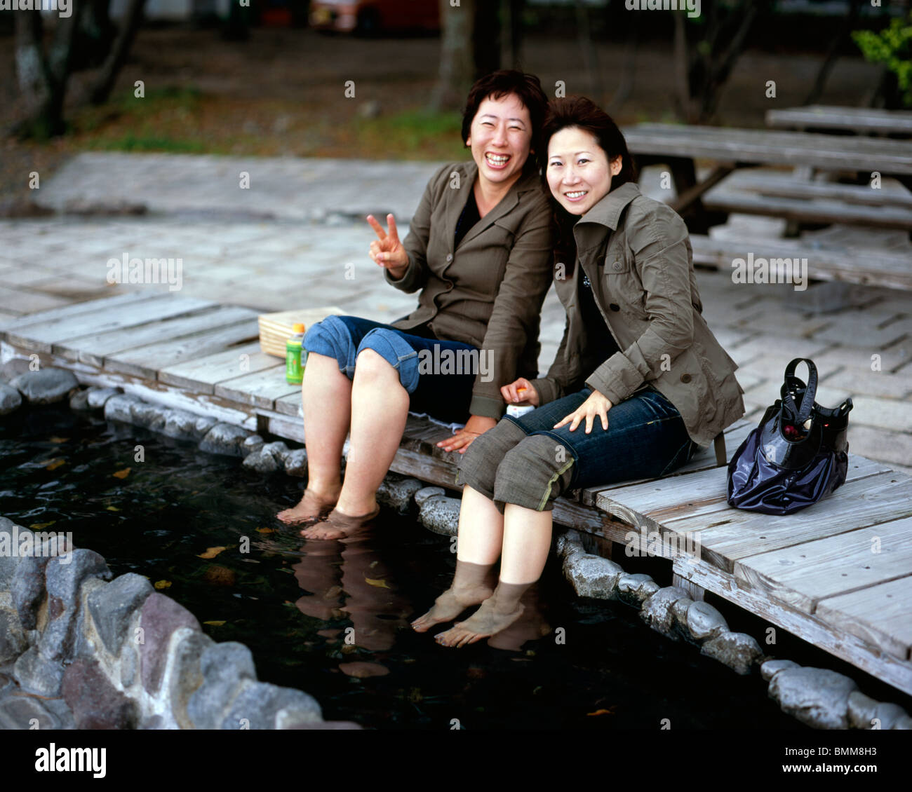 La femme japonaise faire tremper les pieds dans les eaux chaudes à un Beppu onsen Banque D'Images