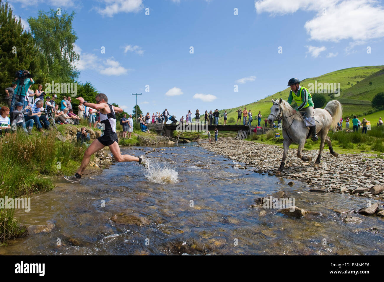Porteur et les chevaux traversent la rivière Ford à Abergwesyn dans l'homme v course de chevaux à Llanwrtyd Wells Powys Pays de Galles UK Banque D'Images