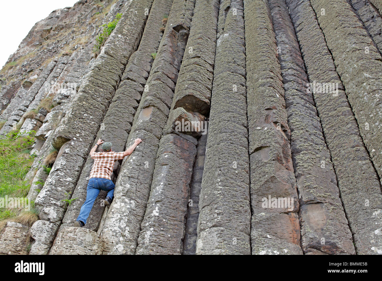 Un homme se faisant passer pour monter les colonnes de basalte de la Chaussée des Géants, en Irlande du Nord Banque D'Images