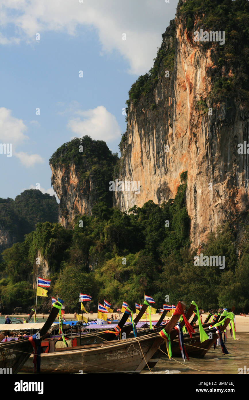 Vertical image de long tail boats sur west Railay Beach, Thaïlande, avec des falaises derrière Banque D'Images