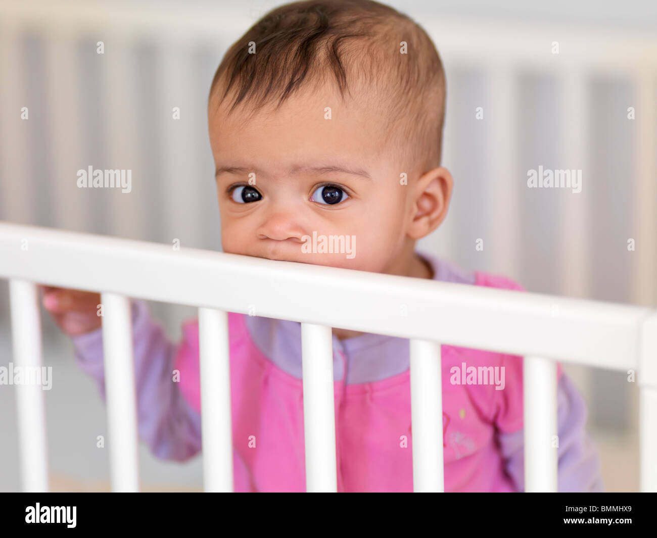 Jolie petite fille de sept mois dans un lit de bébé Banque D'Images