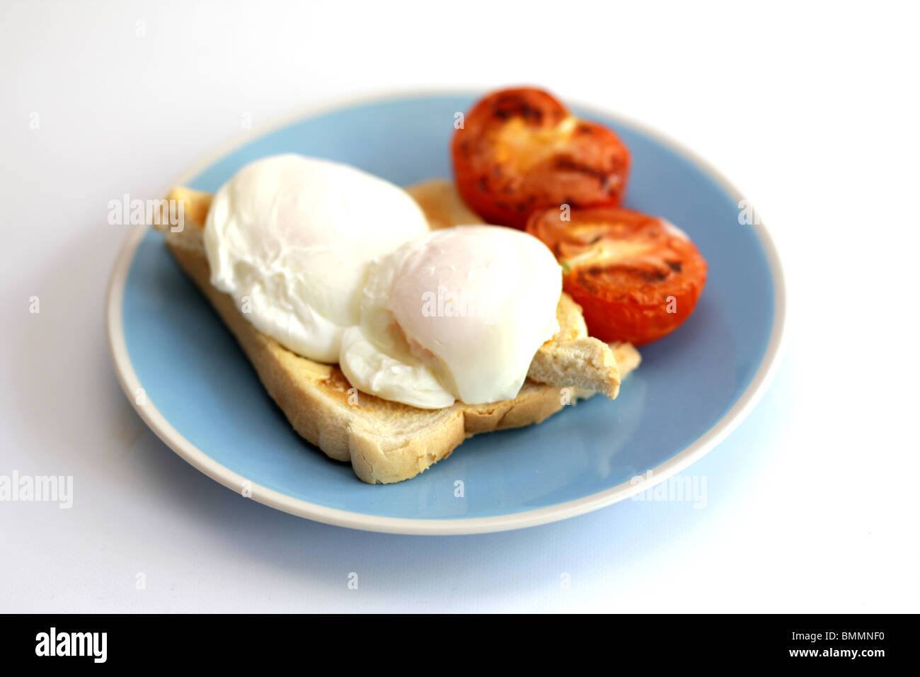 Œufs pochés sur du pain grillé avec des tomates grillées Banque D'Images