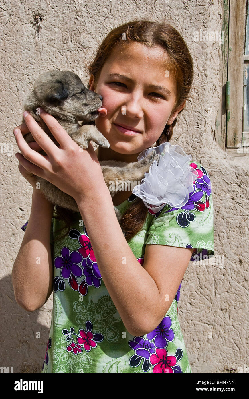 Fille avec un chiot en lui léchant le visage, Khiva, Ouzbékistan, l'Asie. Banque D'Images