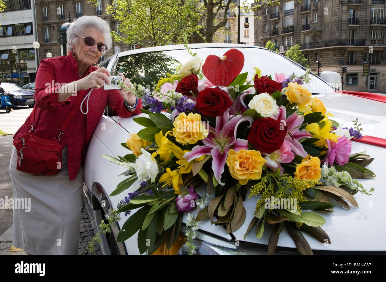 Une vieille dame photographier une voiture de mariage avec un bouquet de fleurs à Paris Banque D'Images