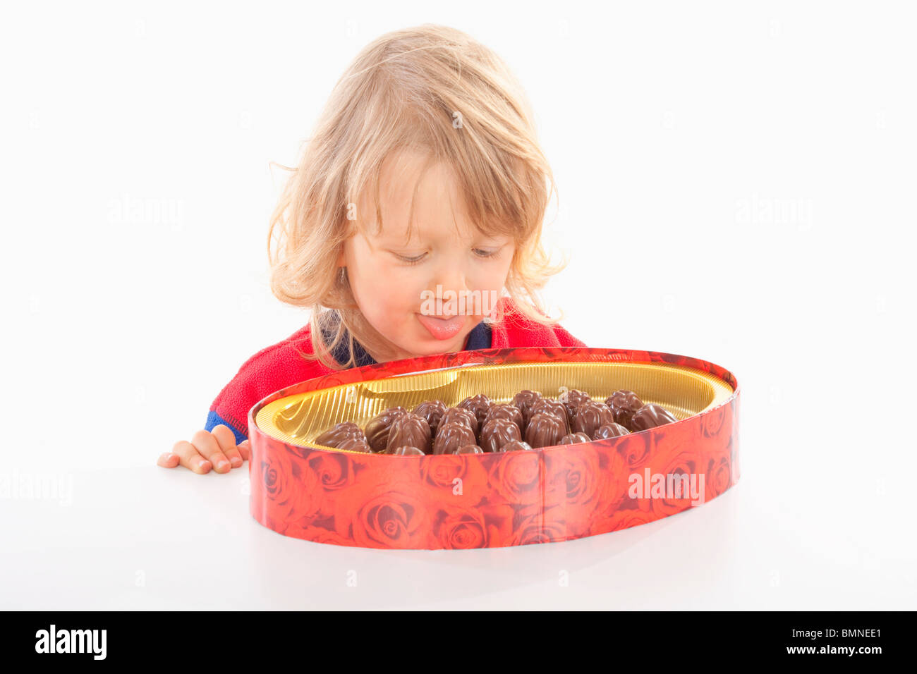 Garçon avec de longs cheveux blonds et une boite de chocolat - isolated on white Banque D'Images