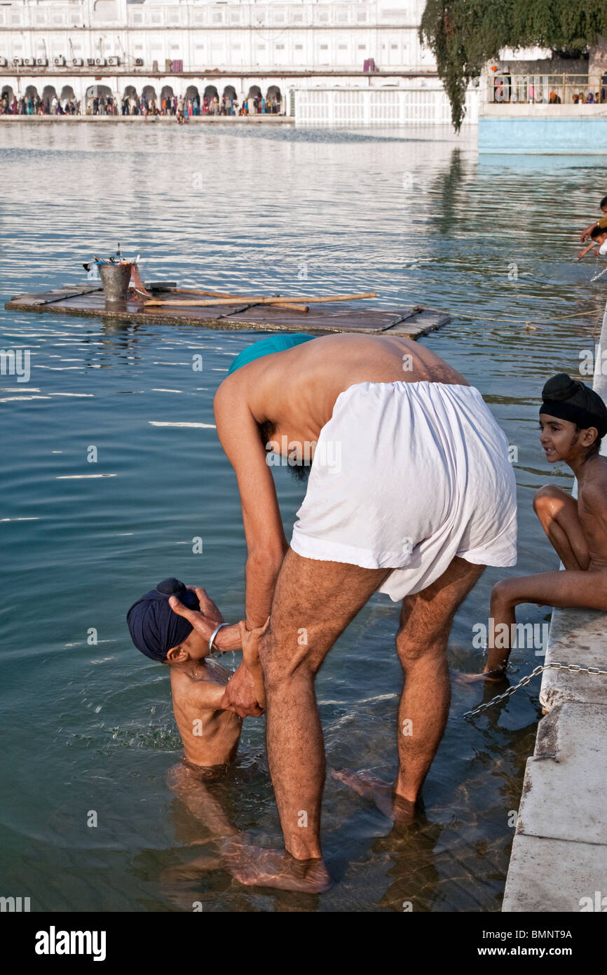 Père et fils se baigner dans le bassin sacré. Le Temple d'or. Amritsar. Punjab. L'Inde Banque D'Images