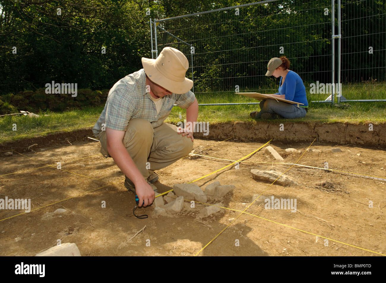 Deux archéologues étudiant de l'université de Lampeter l'excavation et la cartographie à l'âge de fer reste à Llanerchaeron Wales UK Banque D'Images