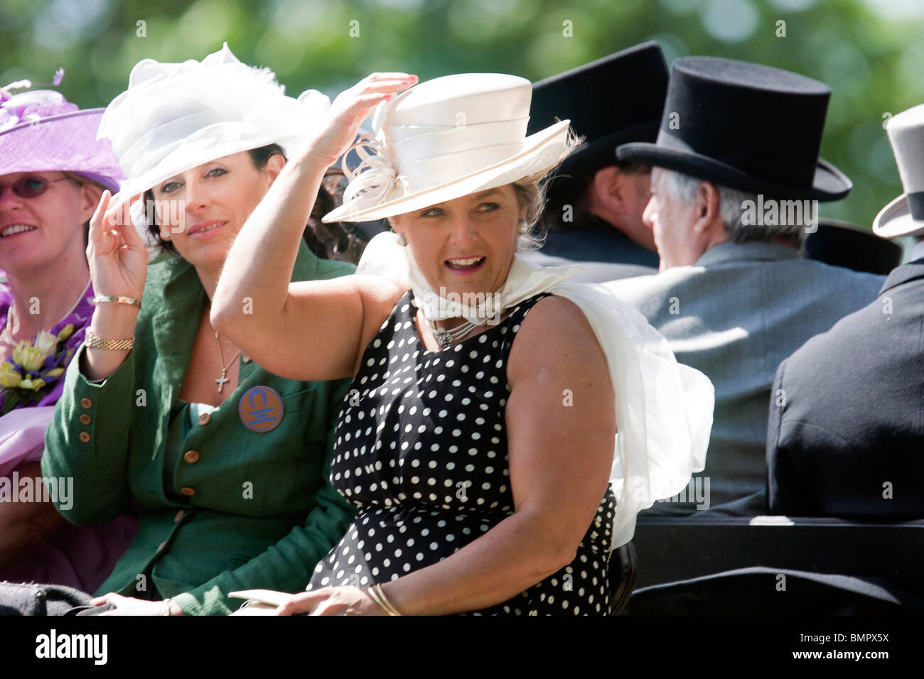 Les amateurs de course arrivent en calèche pour Le Royal Ascot réunion de courses accroché sur leurs chapeaux Banque D'Images