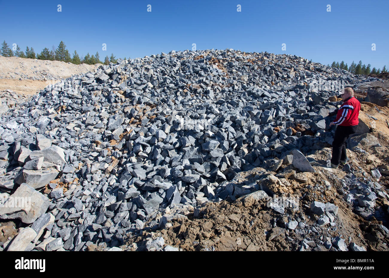 L'homme regardant des tas de roches qui ont explosé à partir de l'assise à la carrière de roche , et plus tard utilisé comme matière première , lors de la fabrication de gravel , Finlande Banque D'Images