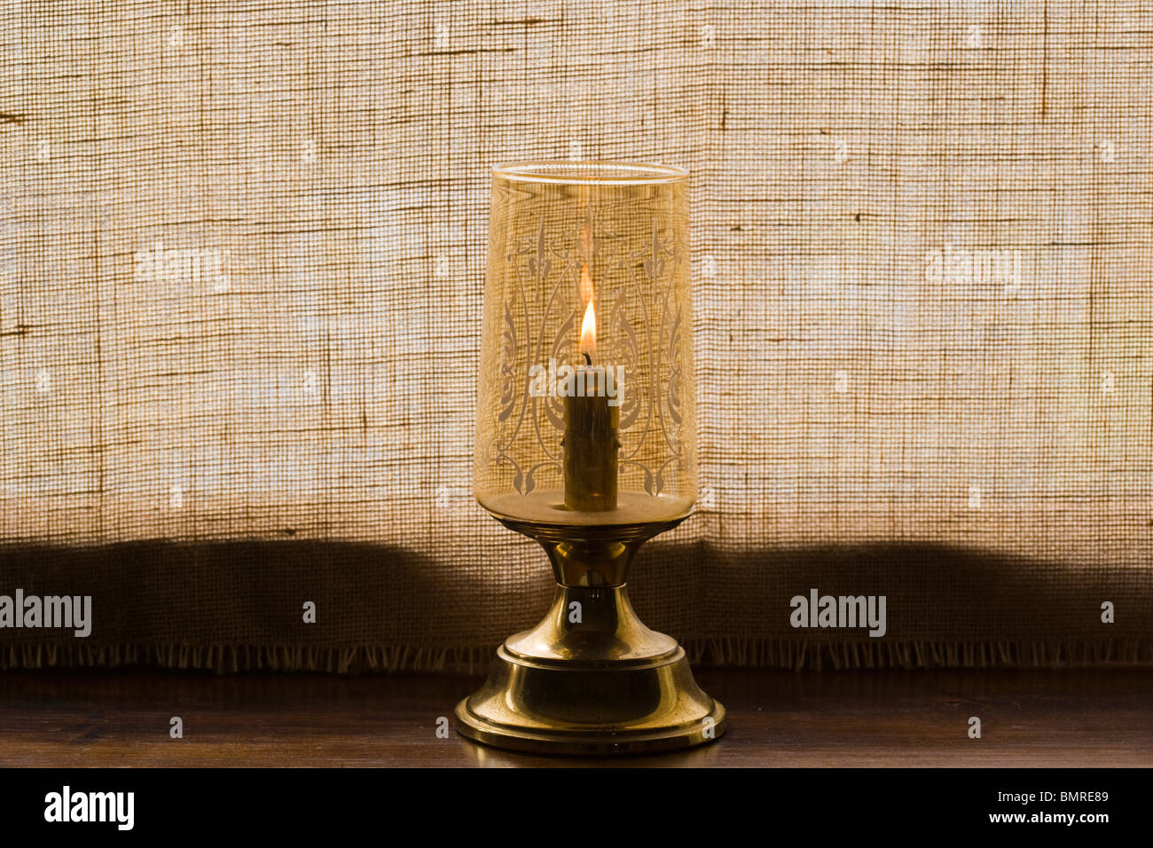Vieille lampe bougie sur windowboard contre fenêtre couverte de Hesse Banque D'Images
