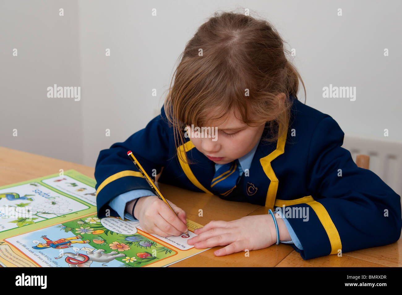 Une jeune écolière termine son travail personnel dans l'écriture de la pratique. Banque D'Images
