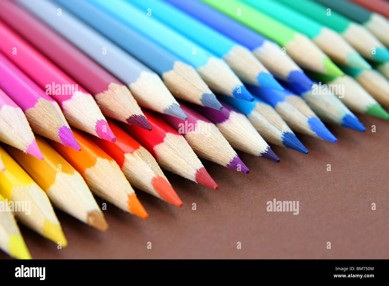 Crayons de couleur dans une rangée isolé sur fond brun Banque D'Images