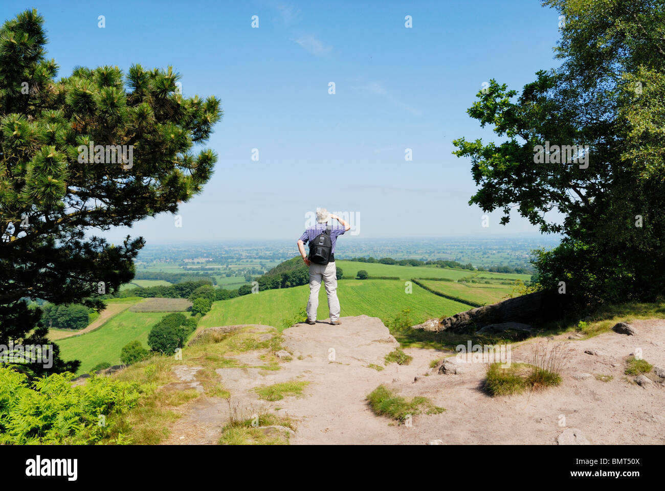 Walker avec la carte d'admirer la vue sur la Plaine du Cheshire du sentier de grès. Banque D'Images