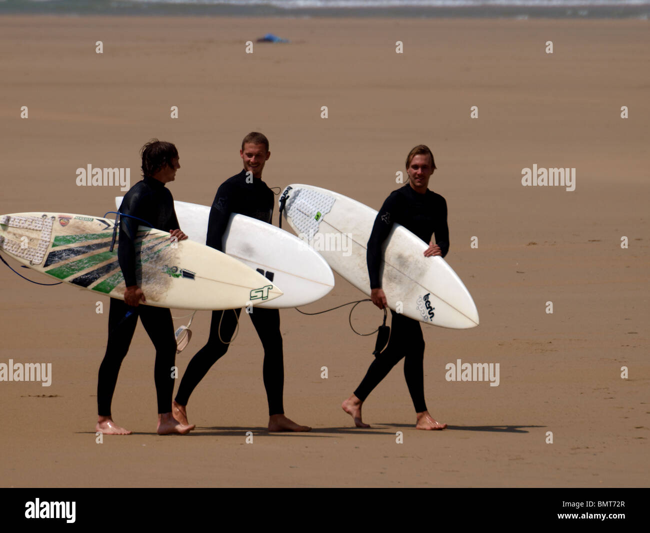 Trois jeunes surfeurs mâles jusqu'à la plage ensemble. Banque D'Images
