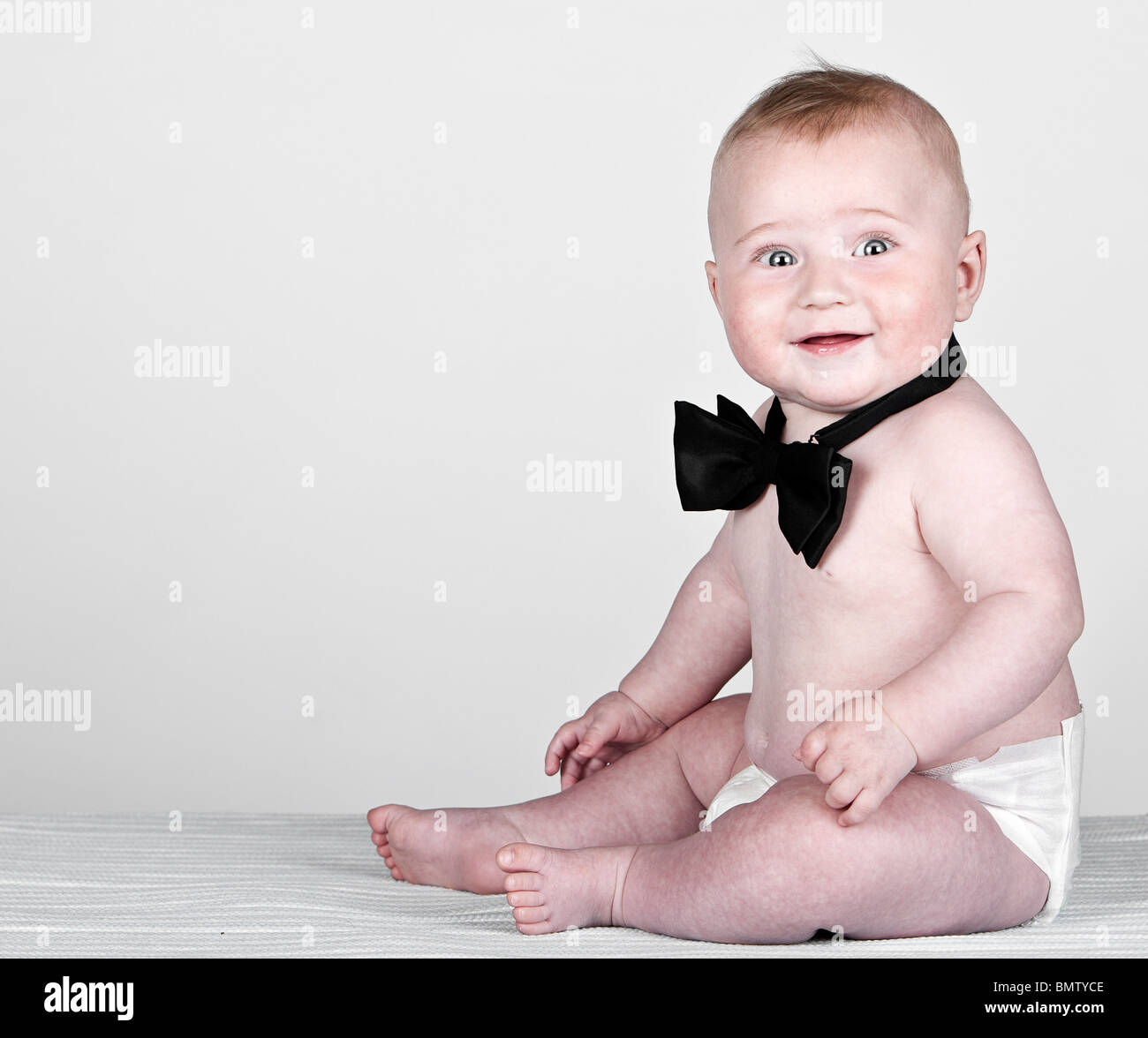 Belle vue d'un petit garçon âgé de 5 mois en Nœud papillon à l'arrière-plan gris Banque D'Images