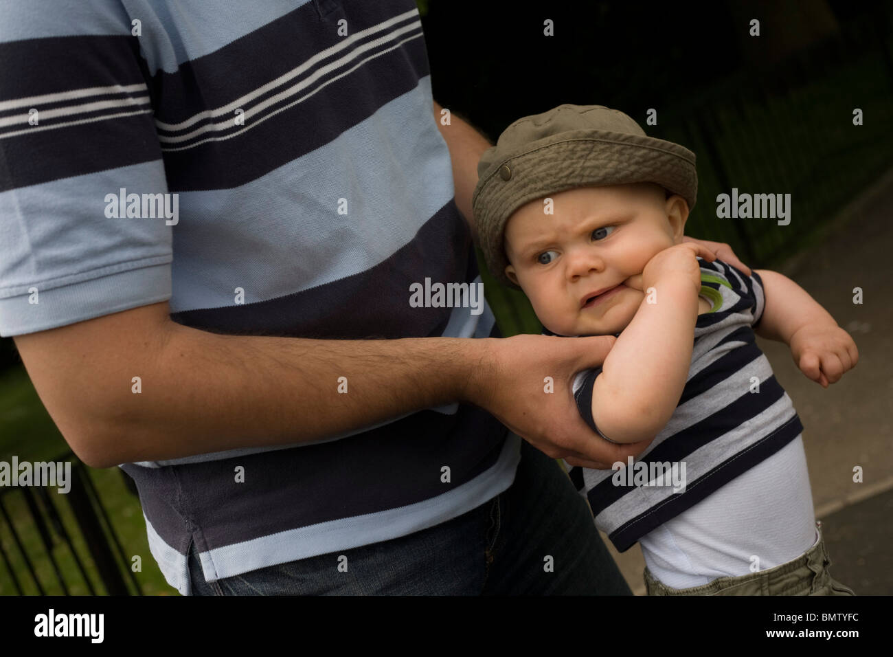 Un enfant âgé de 11 mois est tenue fermement par son papa dans un parc public. Banque D'Images