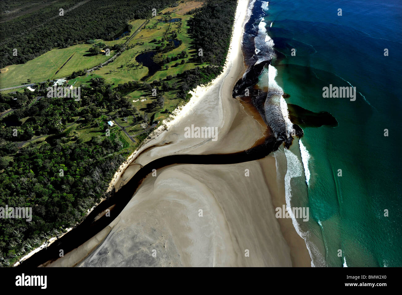Plateau-tree souillé l'eau douce des régions marécageuses de Belongil creek et se déverse dans l'océan Pacifique après la pluie à Byron Bay en Australie. Banque D'Images