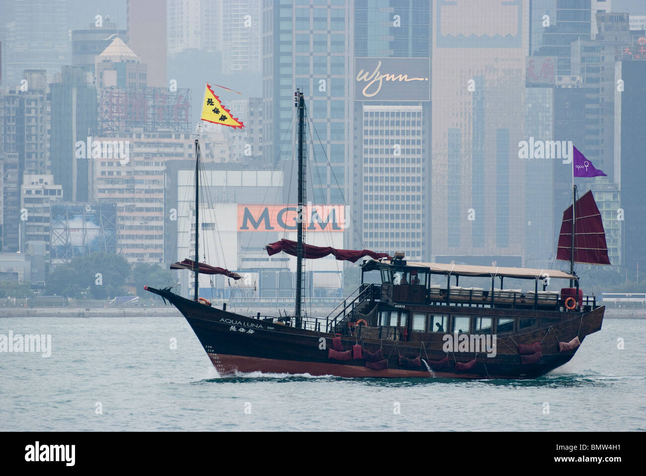 Dans le port de Victoria, une jonque classic sails en face de l'horizon de Hong Kong et les gratte-ciel que la ligne de cette ville historique. Banque D'Images