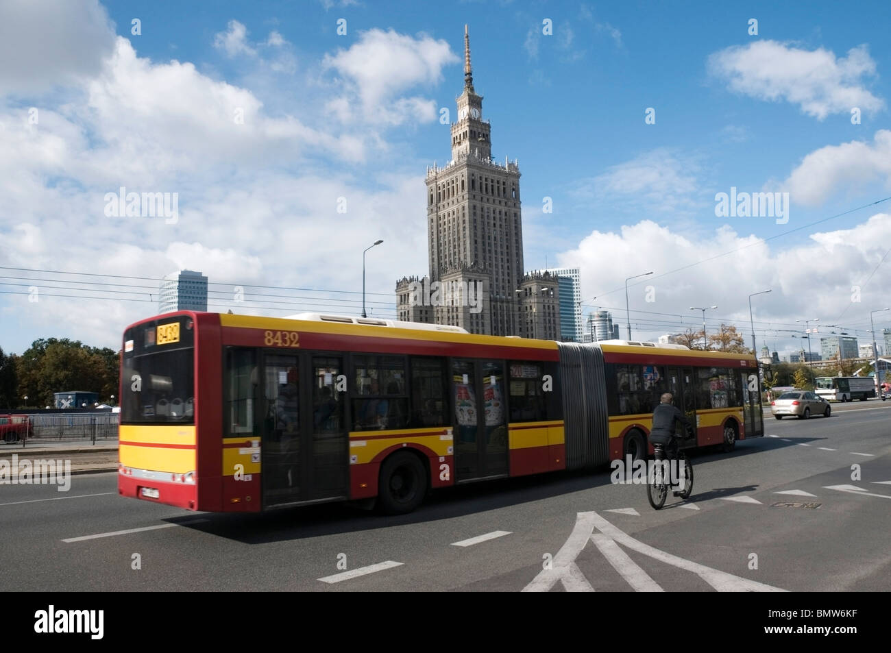 Le rouge et jaune Bendy bus et un cycliste sur la route à l'extérieur du palais de la Culture et des sciences, Varsovie, Pologne, UNION EUROPÉENNE Banque D'Images