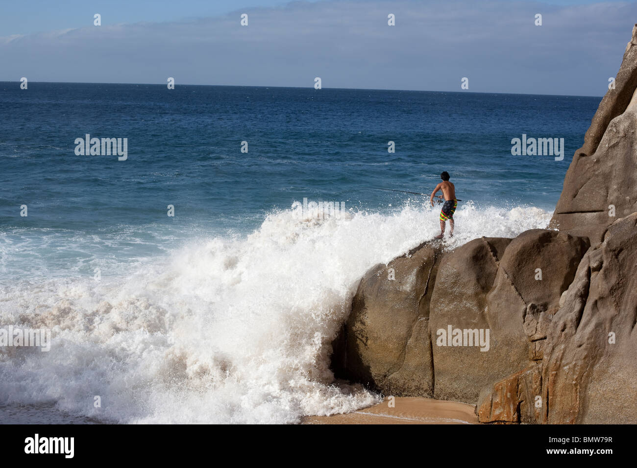 La pêche au large de l'homme des rochers avec de grosses vagues en danger, situation gênante Banque D'Images
