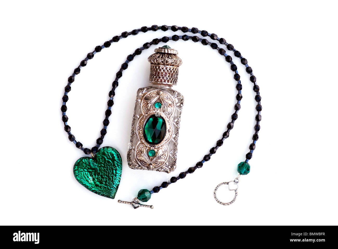 Collier en verre cristal vert émeraude coeur et perles noires avec bouteille de parfum en filigrane argent et vert. Encore plus de féminité avec élégance féminine. Banque D'Images