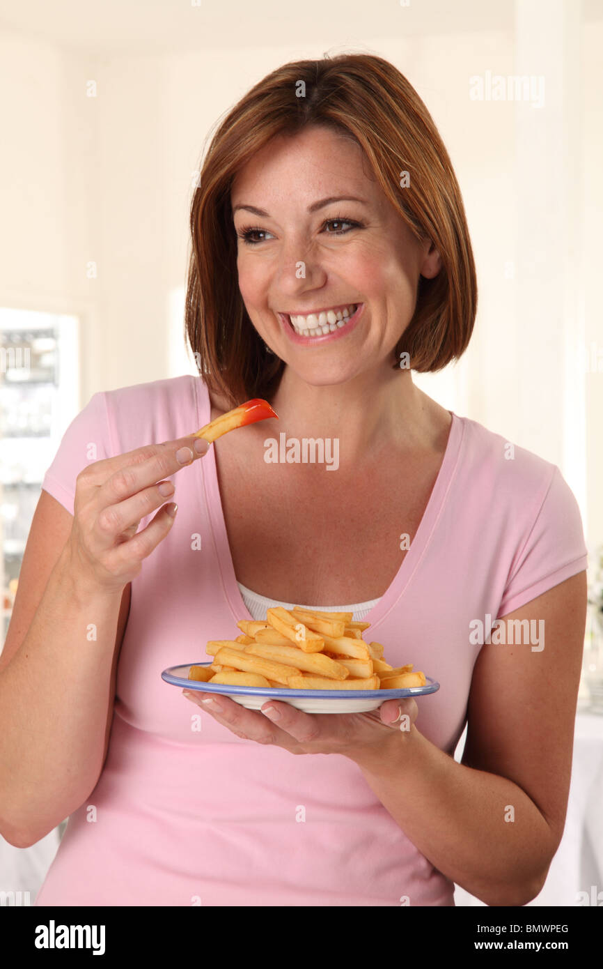 WOMAN EATING FRENCH FRIES Banque D'Images