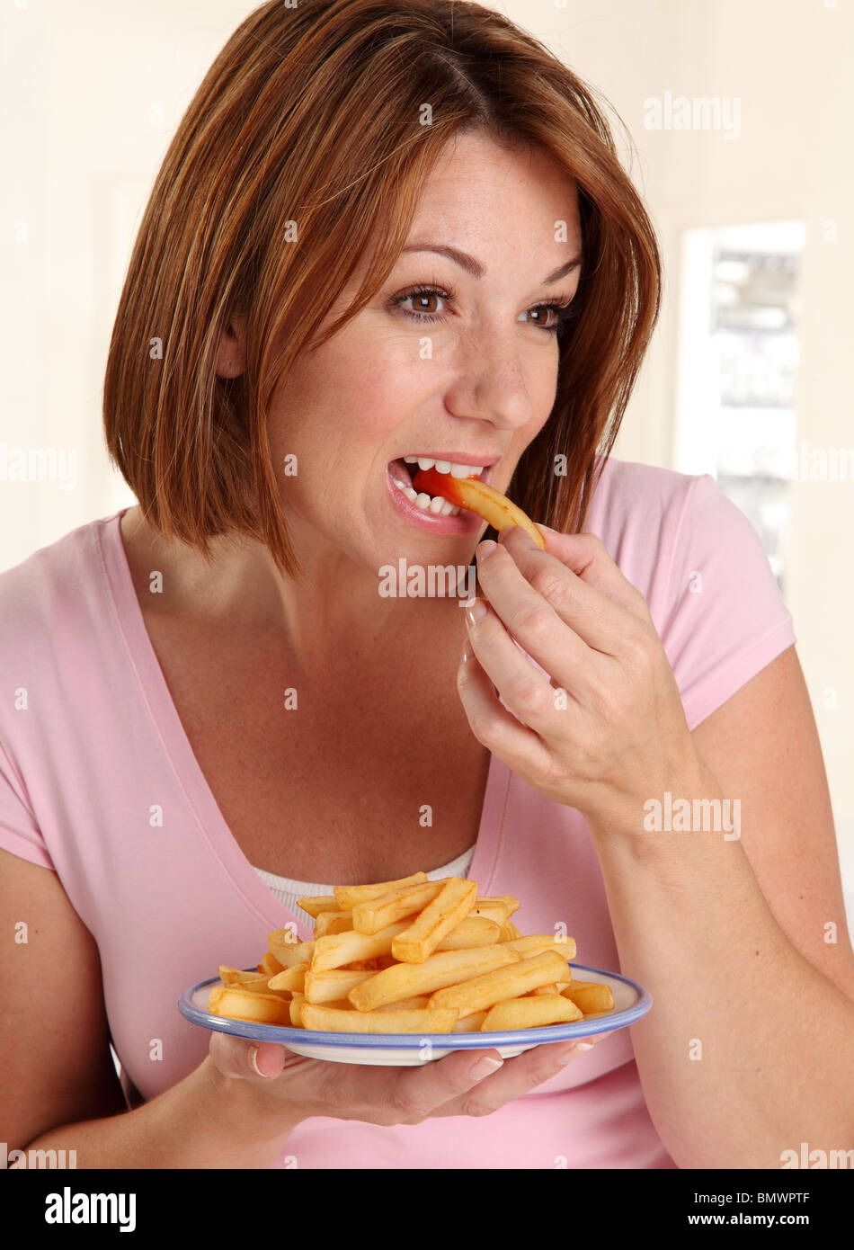 WOMAN EATING FRENCH FRIES Banque D'Images